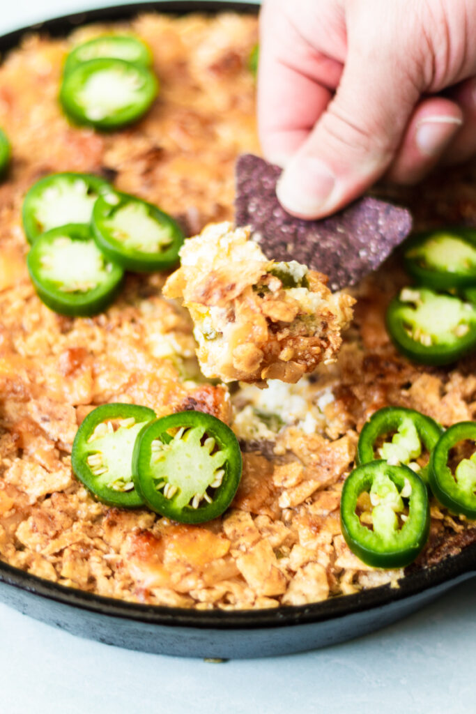 dipping a chip into jalapeno popper dip