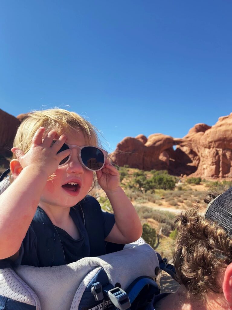 little boy wearing sunglasses in a hiking backpack