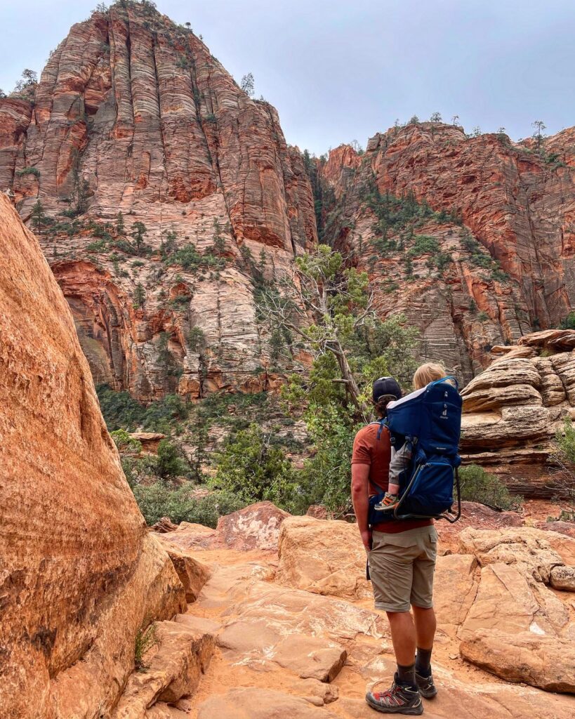 man with a boy in a blue backpack hiking in zion national park