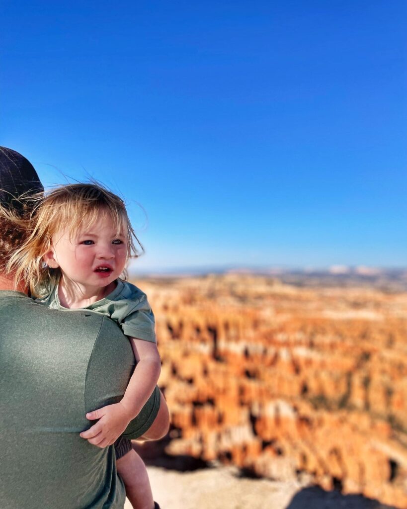 little boy looking over dad's shoulder with hoodoos in the background