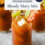 A glass of Bloody Mary garnished with celery, olives, and bacon is shown up close. Text over the image reads Homemade Bloody Mary Mix – So Easy! Try this homemade bloody mary mix recipe at offtheeatenpathblog.com.