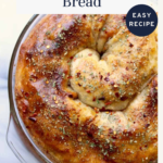 Golden, spiraled pepperoni bread topped with herbs sits in a round baking dish. A text overlay highlights “Pepperoni Bread,” “Easy Recipe,” and “offtheeatenpathblog.com.” Perfect for any pepperoni bread lover!.