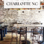 Industrial-style restaurant interior with metal chairs, wooden tables, and exposed brick wall. Text overlay reads: Best Brunch in Charlotte. Website at bottom: offtheeatenpathblog.com.