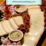 A platter of raclette cheese slices, rolled cured meats, pickles, and two small bowls of sauce, with text reading How to Host a Raclette Dinner Party and fun & interactive dinner party.