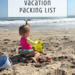 A young child in a pink and yellow swimsuit plays with sand toys on a sunny beach, waves in the background. Text above reads, Your essential family beach vacation packing list.