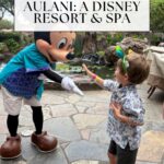 A child wearing sunglasses high-fives Mickey Mouse at Disney’s Aulani Resort & Spa. Text above them reads, An honest aulani review for families: Aulani: A Disney Resort & Spa. The Off the Eaten Path logo is at the bottom.