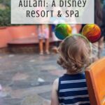 A young child wearing rainbow Mickey Mouse ears stands indoors facing away; text overlay reads “An Honest Aulani Review: A Disney Resort & Spa.” The “Off the Eaten Path” logo appears at the bottom.