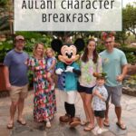 A group of five people, including two children, pose with Mickey Mouse at the Aulani Character Breakfast, surrounded by lush greenery. Text reads “Is it worth it? Aulani Character Breakfast.” Off the Eaten Path logo is at the bottom.
