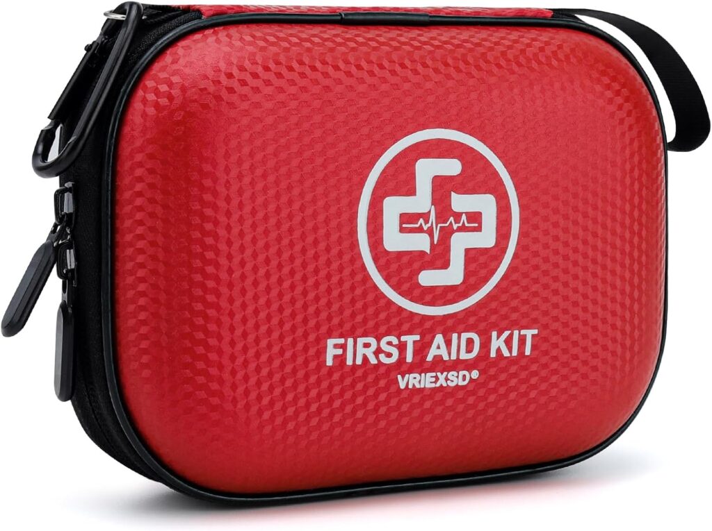 A red, zippered first aid kit case with a white medical cross and heartbeat symbol on the front, labeled First Aid Kit and VRIEKSD. The case has a textured surface and a black handle.