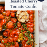 Close-up of roasted cherry tomatoes, garlic bulbs, and herbs in a white baking dish, perfectly capturing the essence of cherry tomato confit. A banner reading Roasted Cherry Tomato Confit and a SO EASY! label in the corner highlight just how simple this delicious cherry tomato confit is to make.