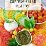 A colorful caprese salad platter with sliced tomatoes, mozzarella, basil, pesto, cherry tomatoes, and yellow tomatoes, arranged on a white tray with a text overlay reading Easy Appetizer Caprese Salad Platter.