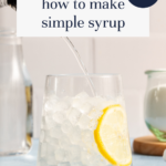 A glass of ice water with a lemon slice is being poured with clear syrup, illustrating how to make simple syrup for your home bar basics. Text reads, how to make simple syrup and home bar basics. Blog URL at the bottom. Additional drinks and tools are in the background.